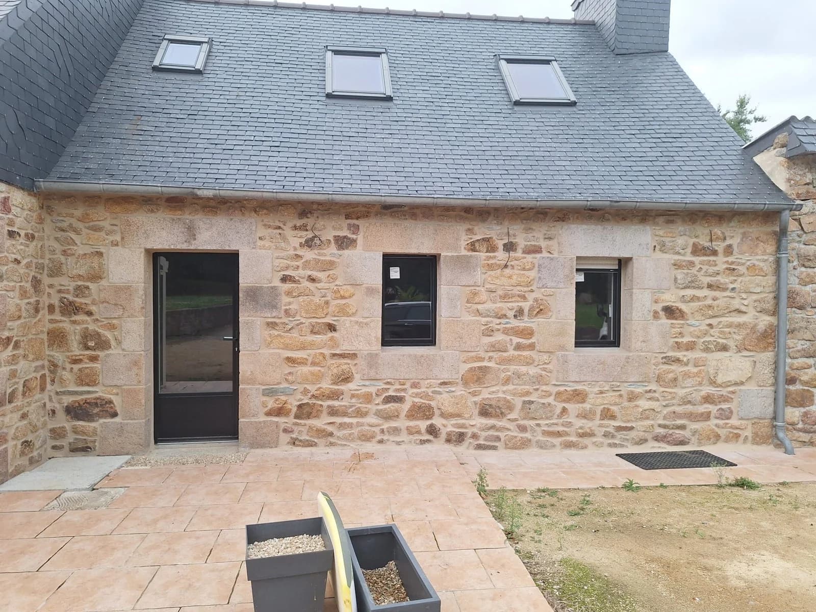 Façade en pierre rénovée et terrasse dallée